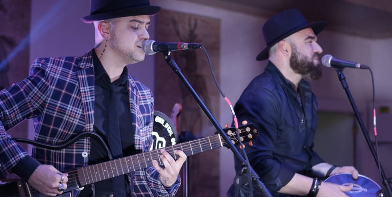 two men playing guitar and singing into a microphone