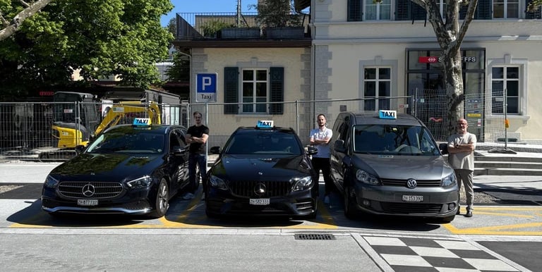 Three taxicars. One grey VW Caddy and two black Mercedes E-Classes with taxidrivers.