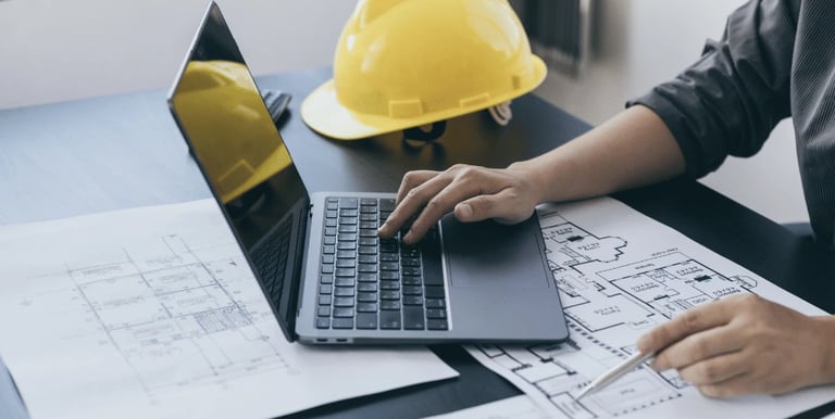 Computador com um capacete de engenharia na mesa