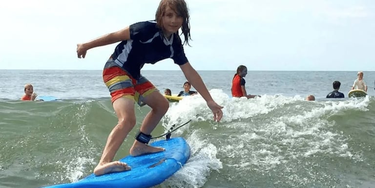 group of surf lesson students in New Hampshire and a boy riding a blue surboard in the foreground