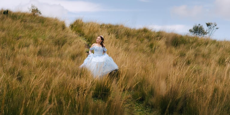 Quinceañera con vestido celeste en un pradp con paja y un cielo azul en Quito Ecuador