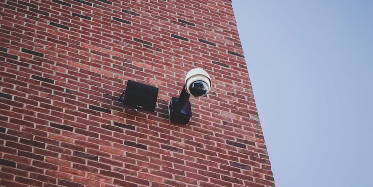 a camera mounted to a brick wall near a brick building