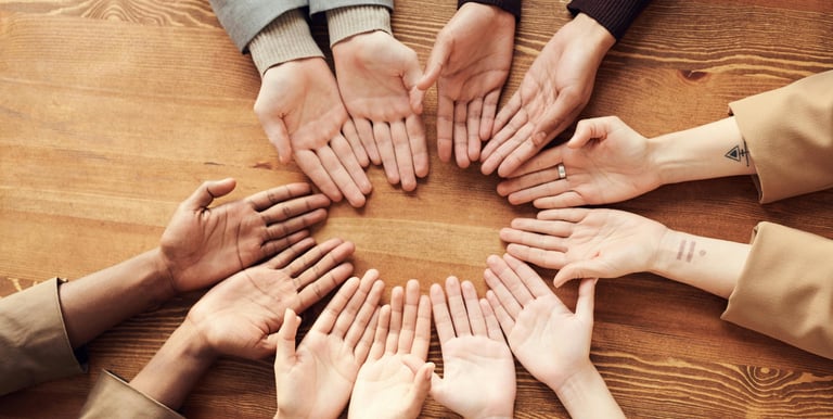 Meerdere handen vormen een cirkel met handpalmen omhoog, beeld van contact en luisteren.
