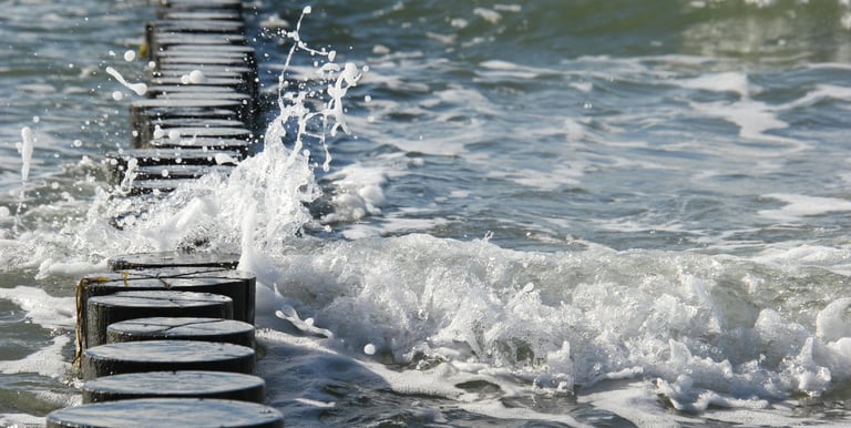 Woeste golven slaan tegen palen in de zee, beeld van onmiddellijke actie en urgentie.