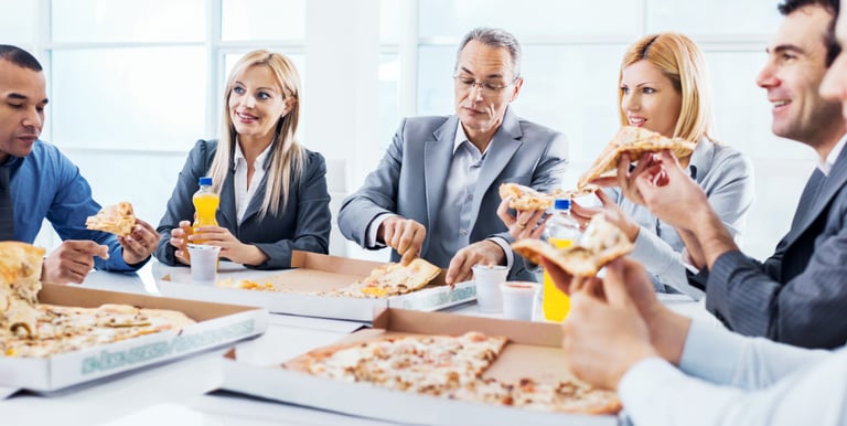 A group of coworkers eating a pizza lunch together. with some juice drinks.