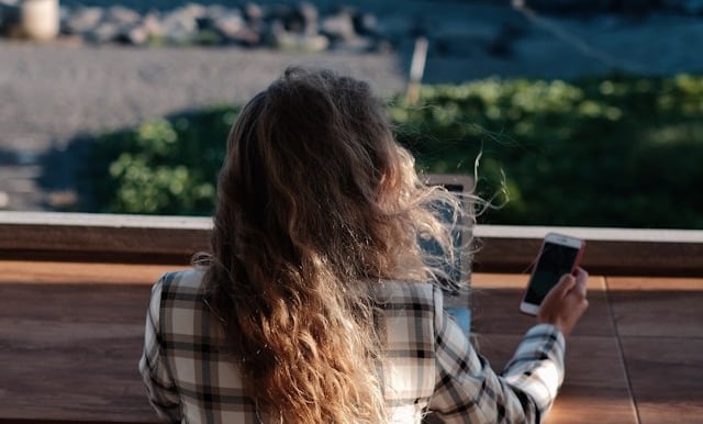 a woman sitting on a bench looking at her cell phone
