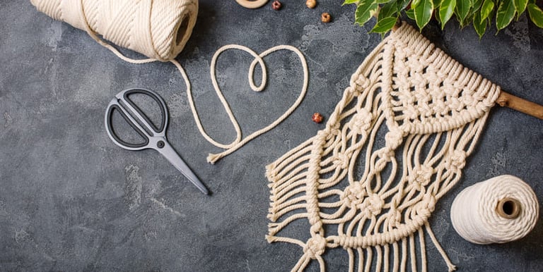 Tapiz de macramé artesanal con cordón de algodón y herramientas.