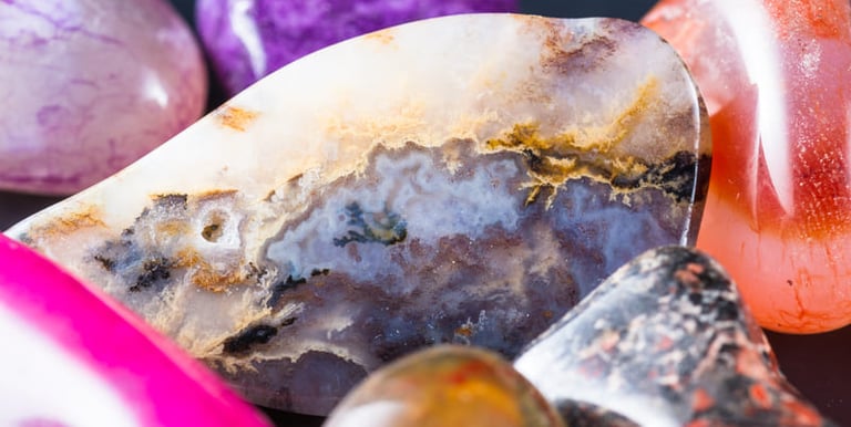 Primer plano de cristales pulidos de sanación y piedras de ágata coloridas con patrones minerales.
