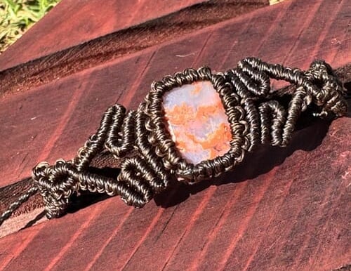 Pulsera de macramé artesanal con ágata naranja natural y tejido detallado en cordón marrón oscuro.
