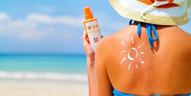 Una mujer en la playa se aplica crema protectora solar con factor de protección solar 50