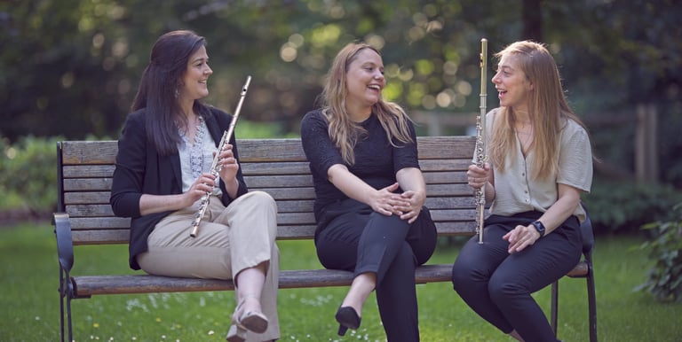 three women sitting on a bench in a park