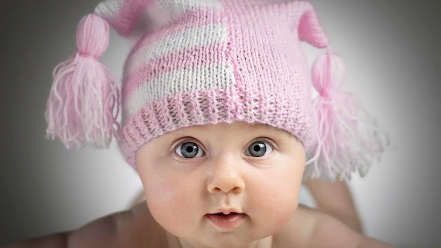 a baby girl wearing a pink hat with a pink and white hat