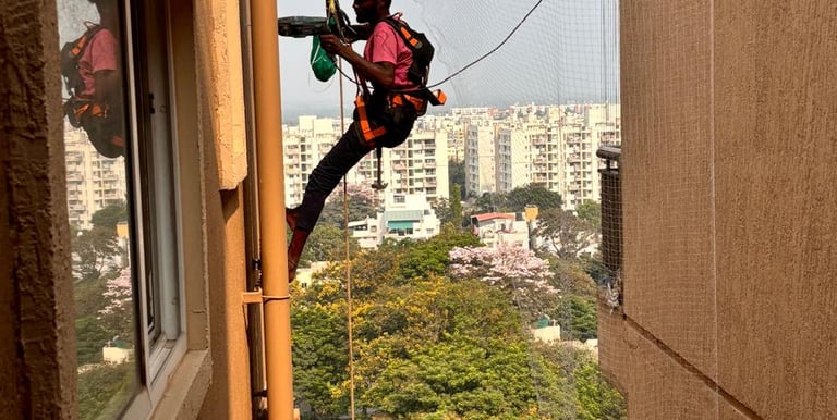 Technician from Arjilli Safety Nets fitting a pigeon net on a high-rise building.
