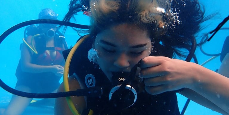 Alumna del curso Open Water DIver entrenando habilidades de máscara y autocontrol en piscina 