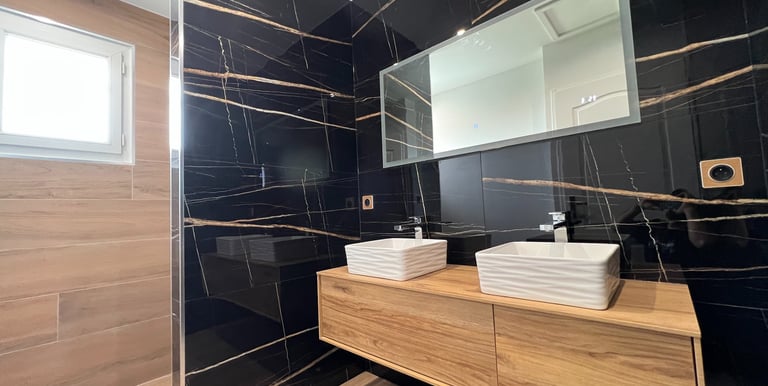 Salle de bain moderne avec double vasque et carrelage effet marbre.
