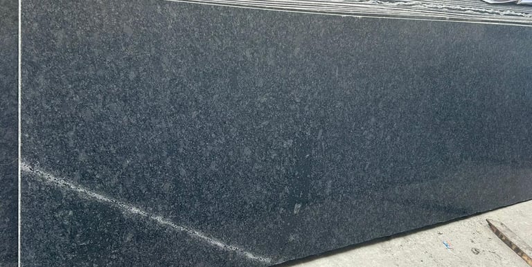 Polished black granite slabs stacked at a warehouse for kitchen countertops and flooring.