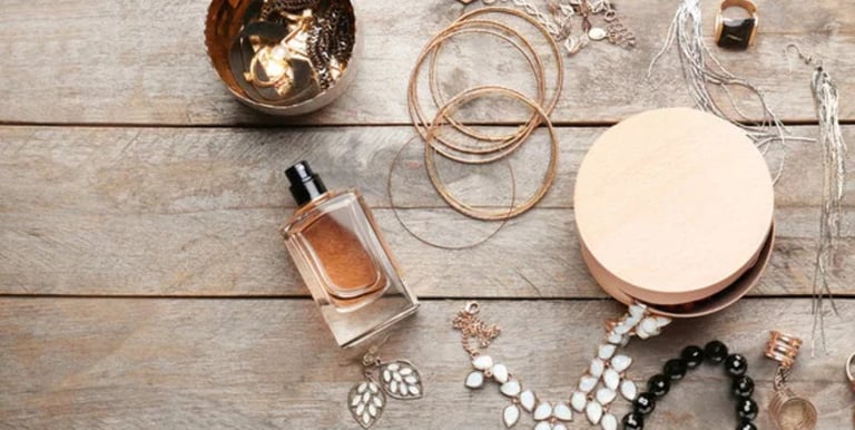 Joyería colocada junto a perfume y accesorios, ejemplo de cuidado para evitar químicos y conservar las piezas por más tiempo.