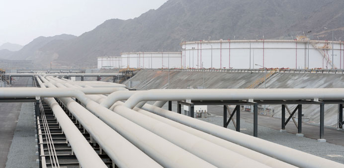 Industrial oil and gas pipeline system with white storage tanks in a mountain facility.