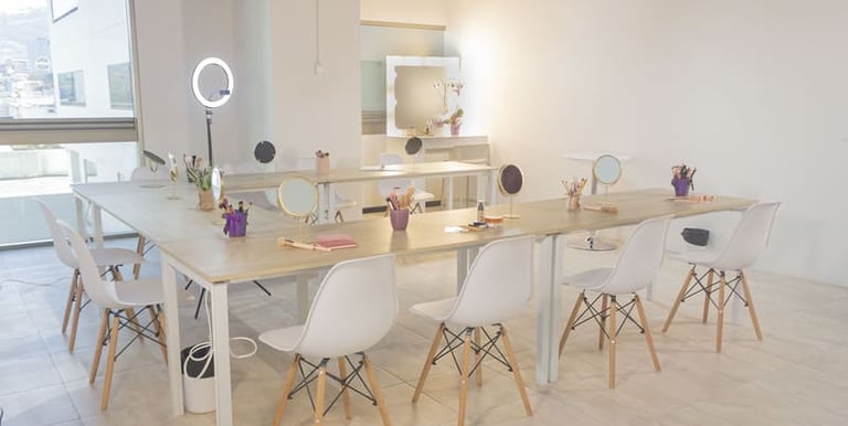 Estudio de taller de maquillaje profesional con espejos de tocador y juegos de pinceles sobre mesas