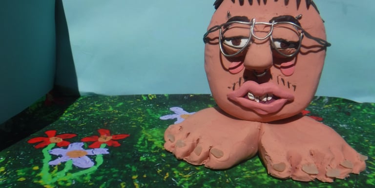 Surreal handmade clay sculpture of a head with glasses and bare feet on a floral background.