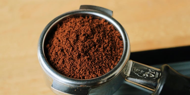 Finely ground espresso coffee beans in a stainless steel portafilter ready for brewing.