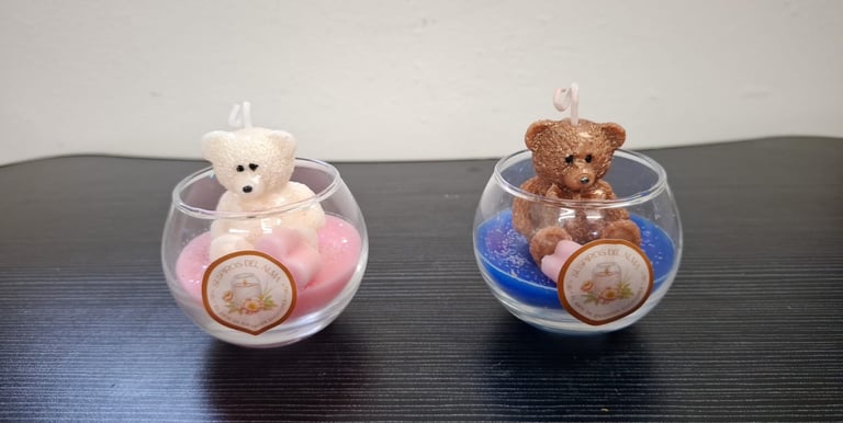 Handmade white and brown teddy bear candles in decorative glass jars with pink and blue wax.