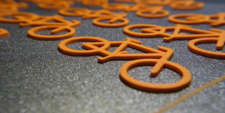 a bunch of orange 3d prints on our 3d printer buildplate