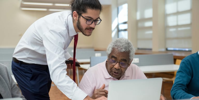 A younger man helping an older man with a computer