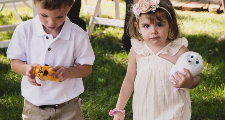 A young flower girl and ring bearer playing on the grass at an outdoor summer wedding. Athens, Oh