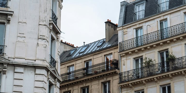 Immeubles haussmanniens avec balcons en fer forgé sous un ciel clair, architecture typique de Paris