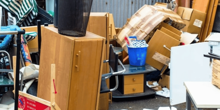 Trash, old furniture, and debris being picked up from a homeowners property.