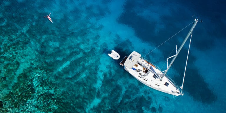 a sailboat in the water with a person swimming in the water