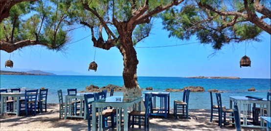 a table with chairs and tables in front of a tree in chania