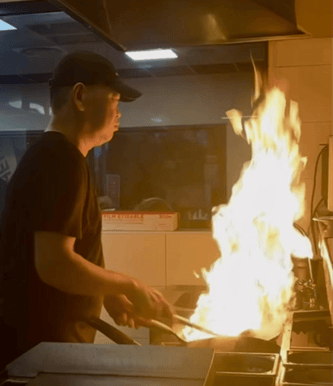 a man is cooking in a restaurant with a fire