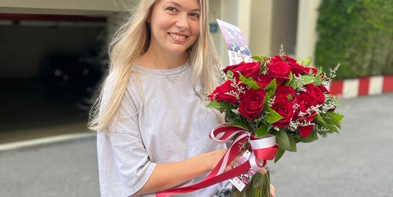 a woman holding a bouquet of red roses