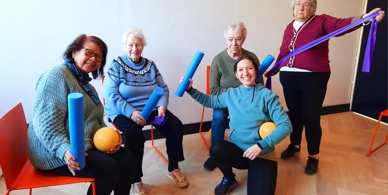 Groepsfoto van instructeur met oudere dames die poseren met materialen die gebruikt worden in de les