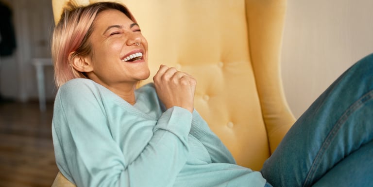 femme heureuse riant dans un fauteuil jaune.