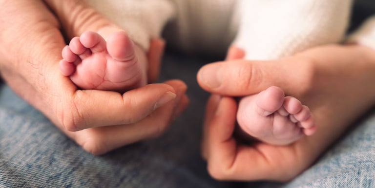 Mains des parents tenant les pieds de leur bébé, naissance Paris 9