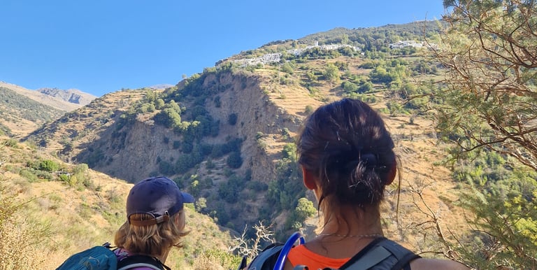 two people standing on a mountain top with backpacks