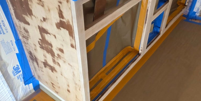 Sanded kitchen cabinets prepared for painting with 3M masking film and blue painter's tape.