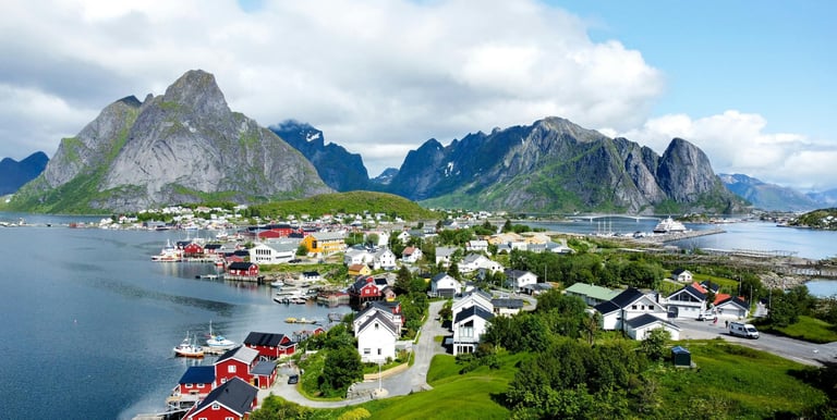 Aerial view of a scenic fishing village in Lofoten Norway with colorful houses and rugged mountains.