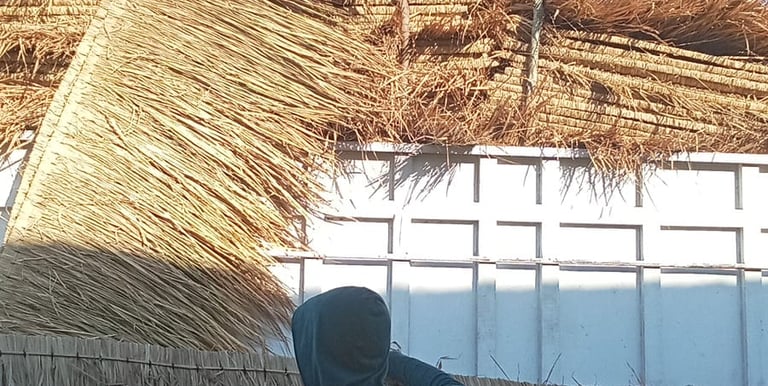 a man and woman working on a straw - woven roof