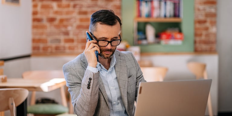 Tomasz Majdosz, man talking on the mobile phone while looking at his laptop