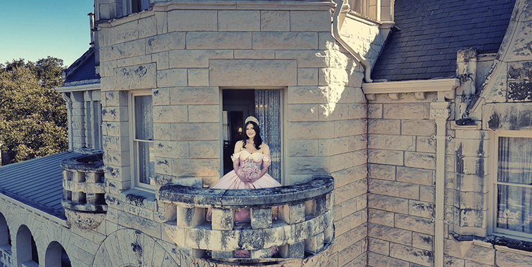 a woman in a pink quinceanera dress sitting on a balcony