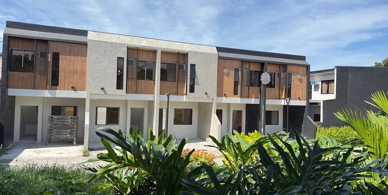 Modern, serene townhomes in Pandi, Bulacan, featuring warm wood accents and lush tropical greenery.