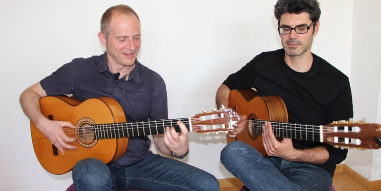 master and student men playing flamenco guitar together