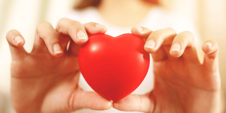 Dos manos en primer plano sosteniendo con cuidado un corazón de juguete. Da a entender que se cuida 