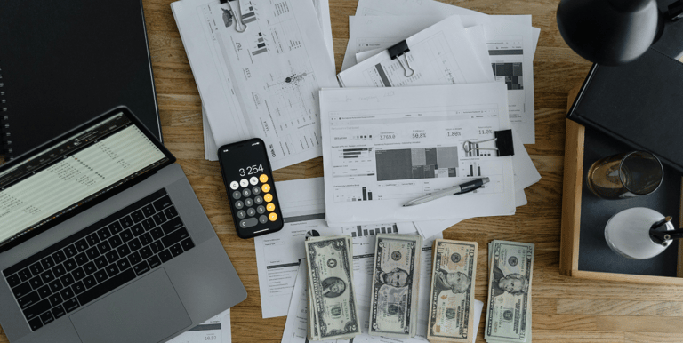 computer on table with financials and money