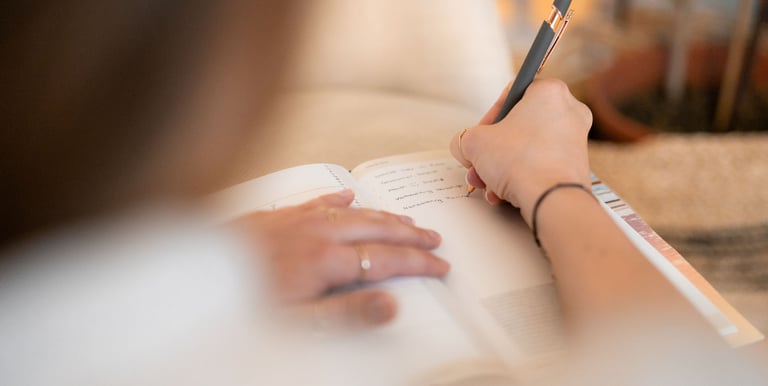 Frau schreibt Notizen ihres Stressmanagement-& Burnout Prävention Beratungsgesprächs in ein Buch