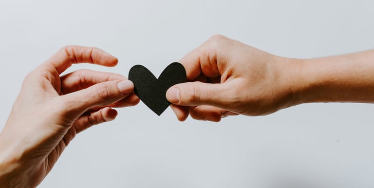 two hands holding a paper heart shaped paper cutout